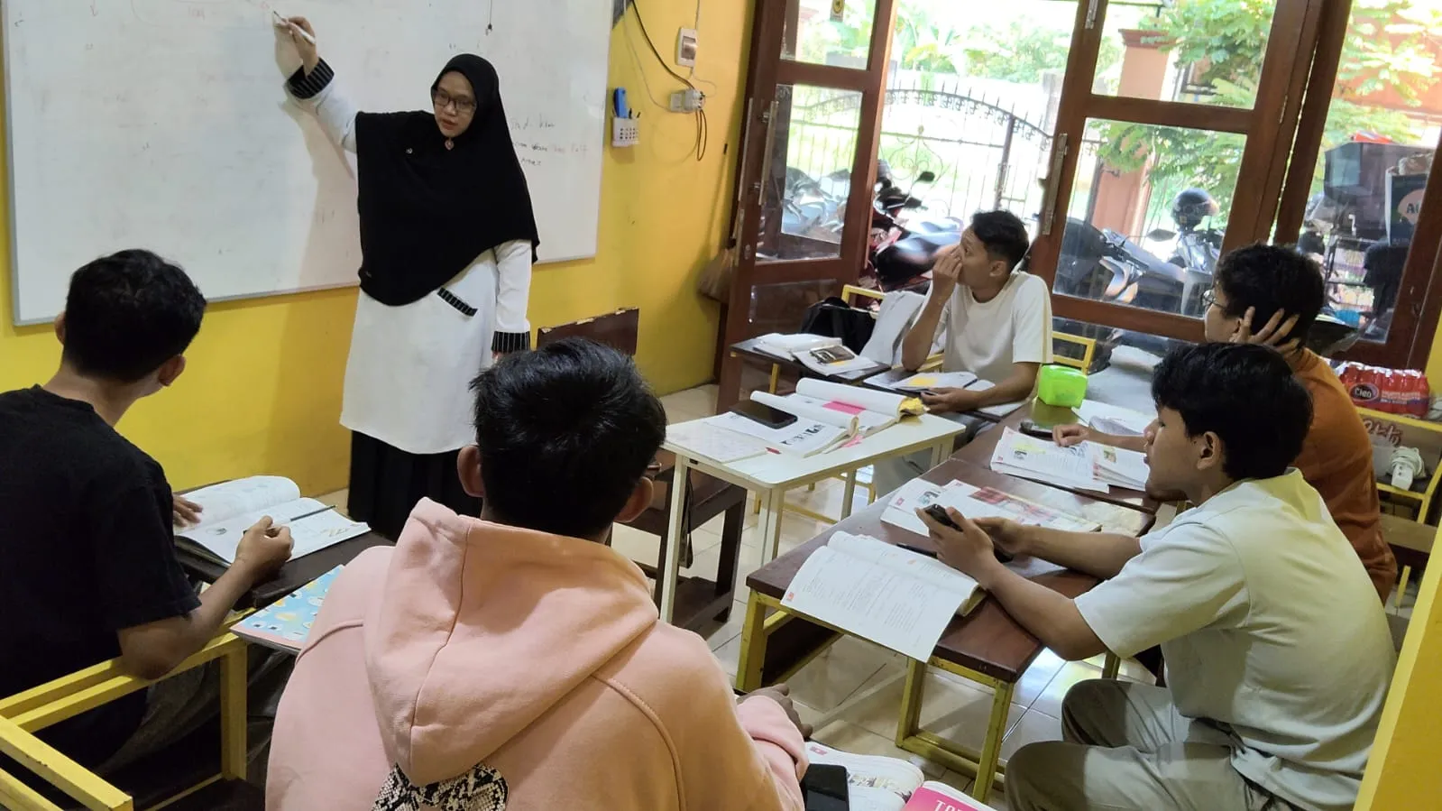 Tutor QEC mengajar materi Bahasa Jerman di papan tulis